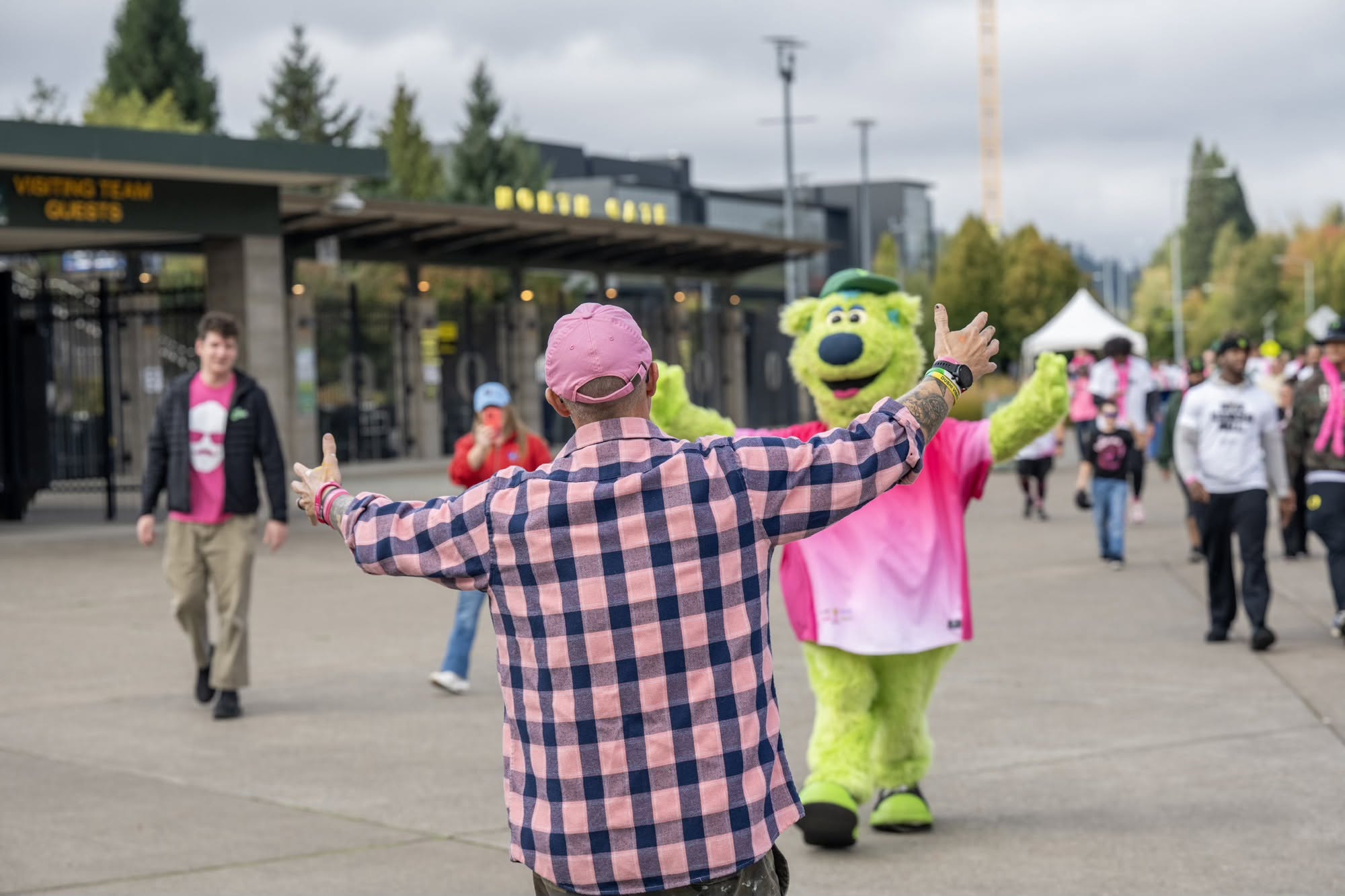 Men Wear Pink ambassador greeting the Oregon Ducks mascot in a pink jersey